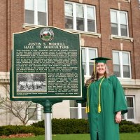 Michigan State University student Lauren Heberling outside of Morrill Hall of Agriculture on campus in her graduation cap and gown.