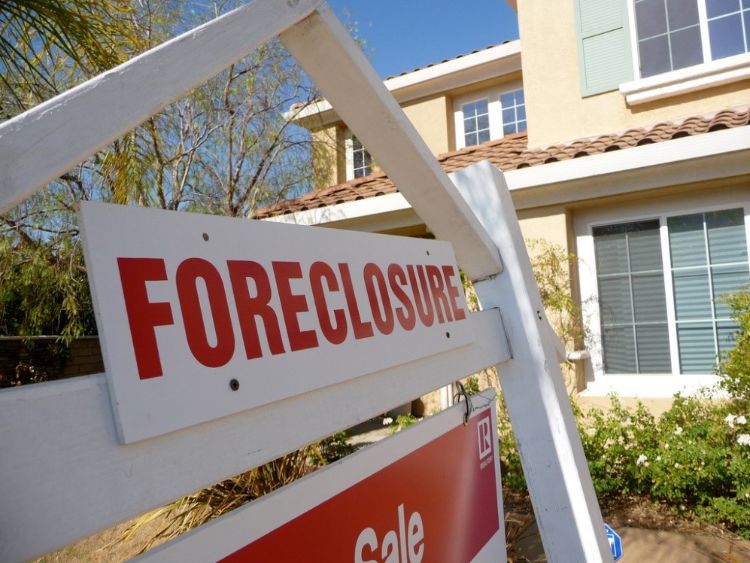 a sign in front of a house stating foreclosure