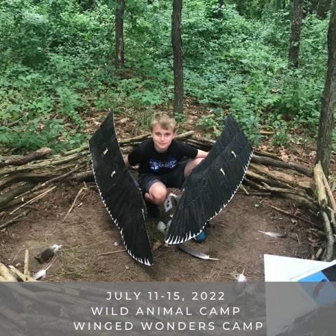 Camper sits in large human made bird nest with fake wings.