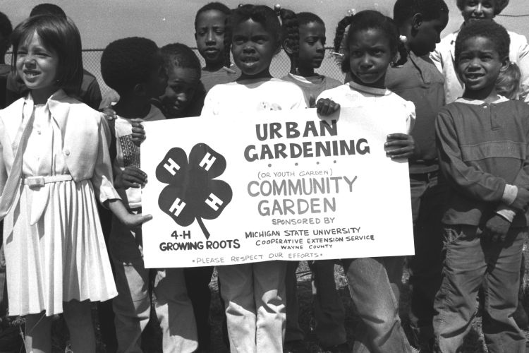 Youth holding up a 4-H sign about their community garden project in Detroit.