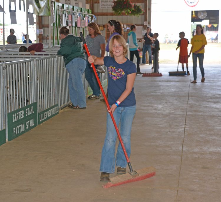 Girl sweeping floors in barn