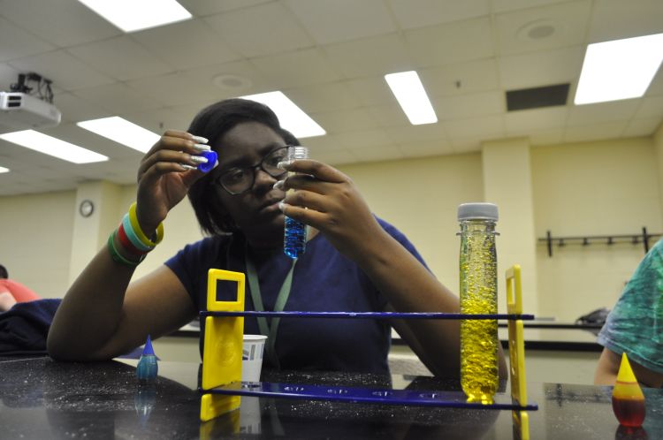 Young girl holding up test tube.