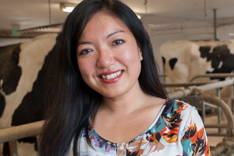 A headshot of a woman with cows in the background.