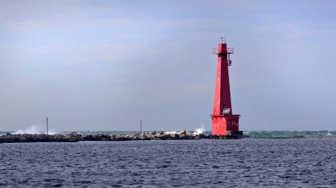 Photo of a pier and lighthouse surrounded by water.