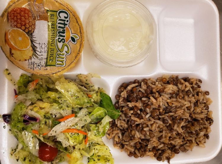 A school lunch containing salad, juice, and mjudara.