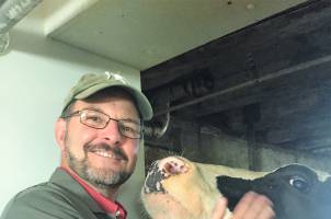 Photo of Extension Educator, Phil Durst, posing with a dairy cow.