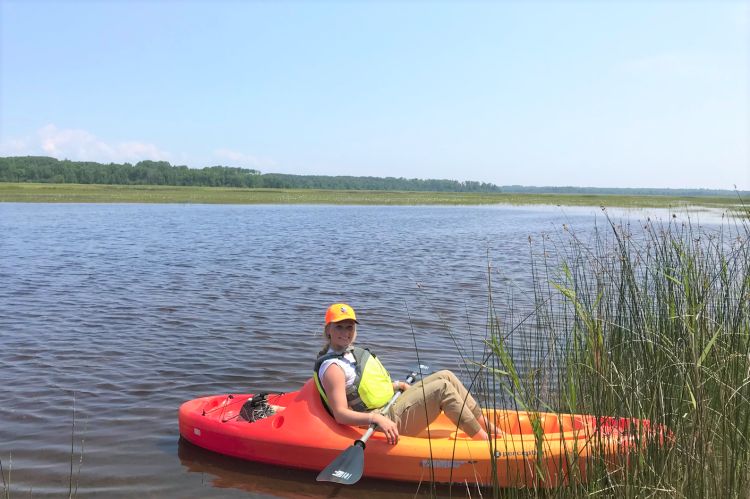 MSU student Kailee Pearson in a kayak sampling wild rice vegetation.