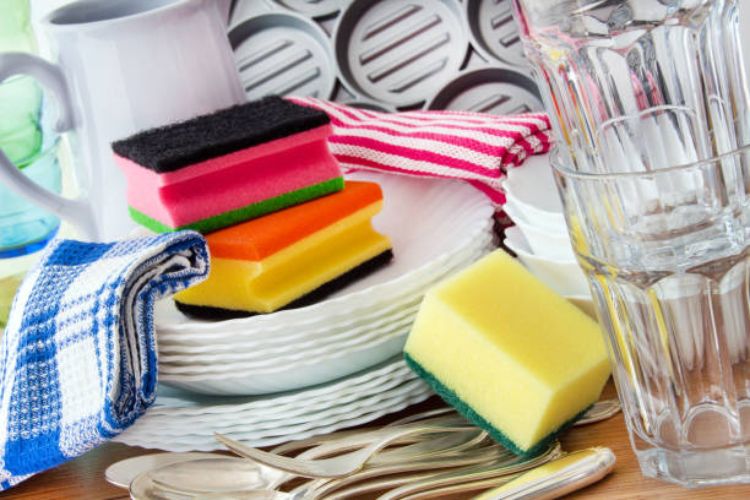 Different sponges near a pile of dishes.