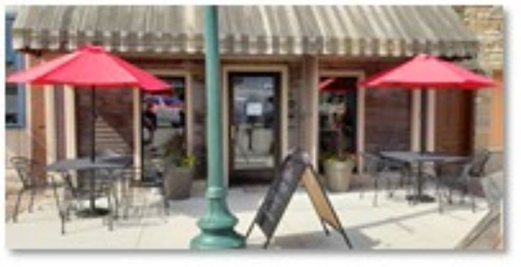 black tables with red umbrellas outside a restaurant on a sidewalk