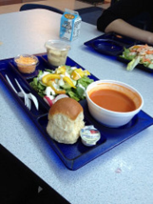 School lunch with roll, soup, salad, cheese, and milk.