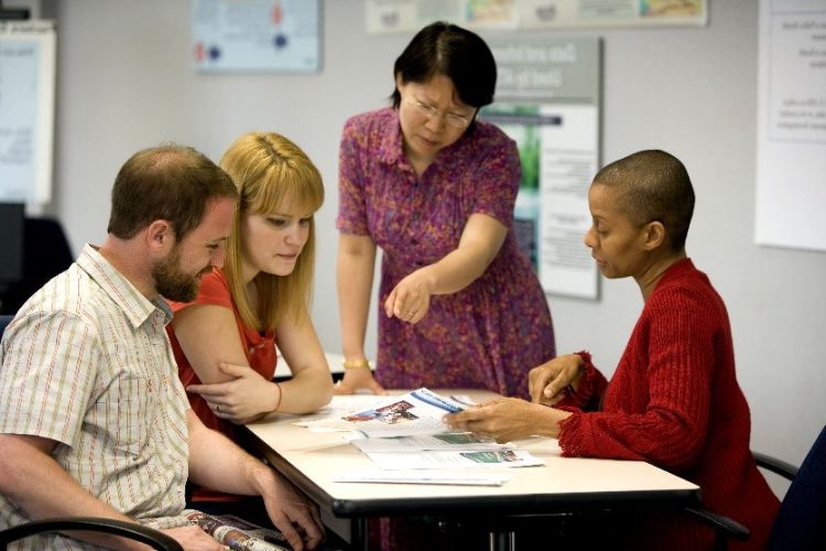 Four individuals sitting at a work table discussing something.