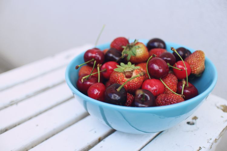 Blue bowl filled with strawberries and cherries.