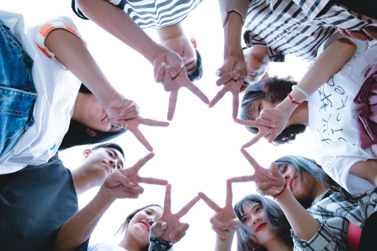 Youth standing in a circle forming a start with their fingers.