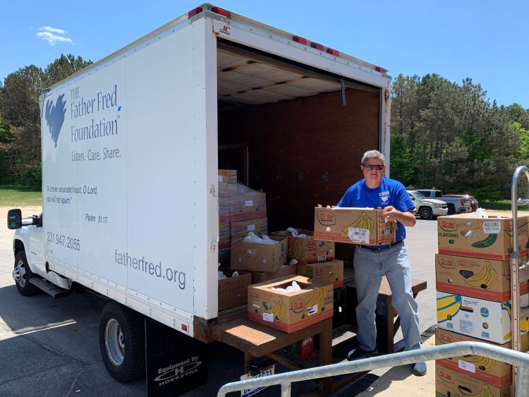 A Father Fred staffer unloading food boxes from a truck.