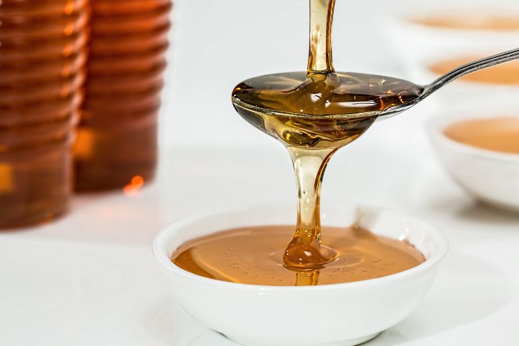 Honey being poured into a white bowl.