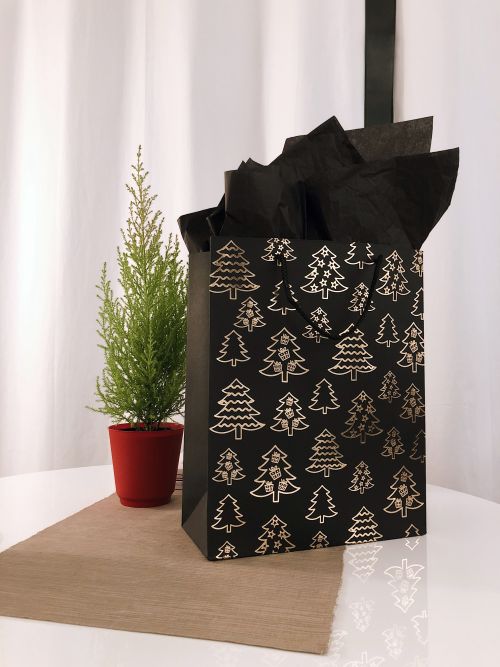 Gift bag next to miniature Christmas tree.