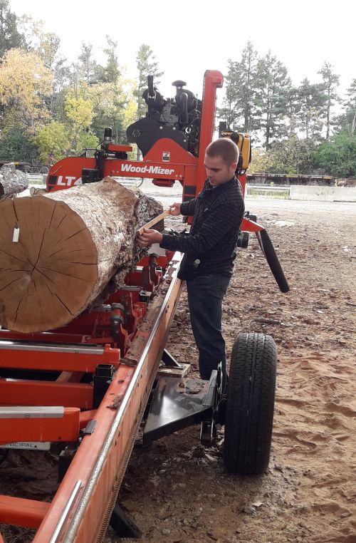 MSU forestry student, Joe Noeske, uses a Biltmore stick to scale a white oak log, recovered from a tree taken down on campus by the MSU Shadows Program.