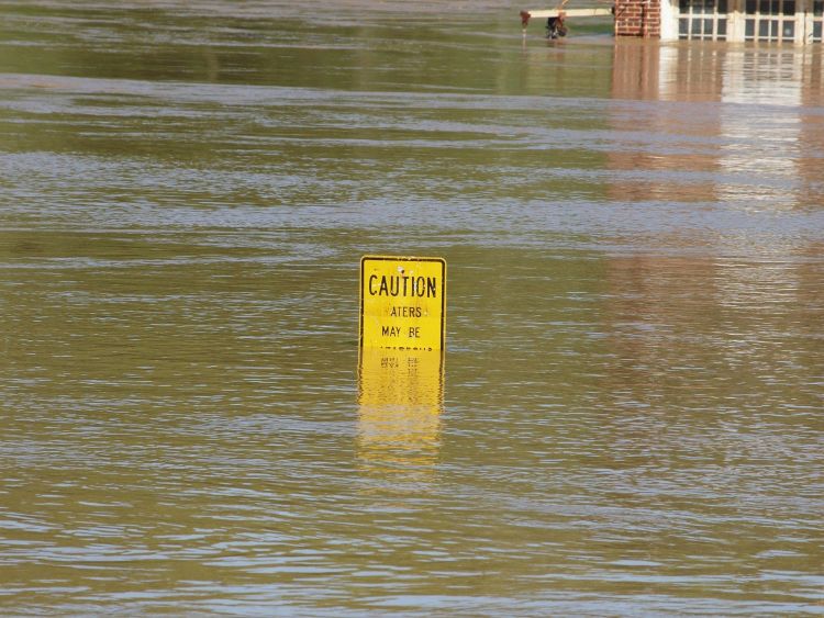 A caution sign floating in floodwaters.
