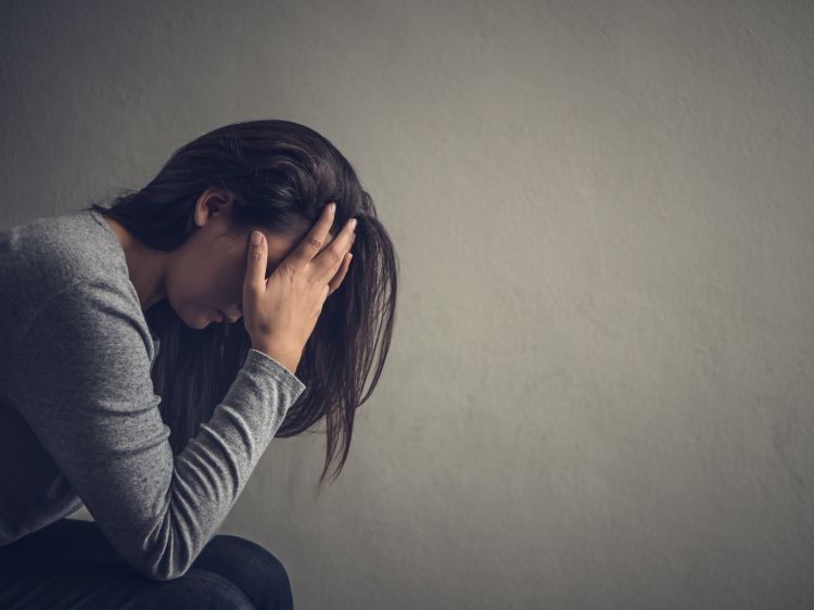 Woman sitting with her head in her hands, visibly stressed.