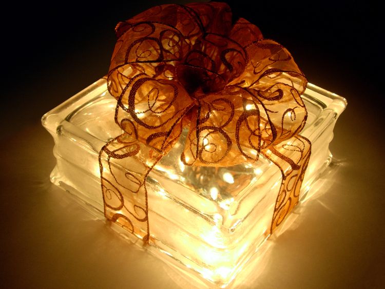 A handmade gift of a see-through cube that is filled with lights and has a big red bow on top.