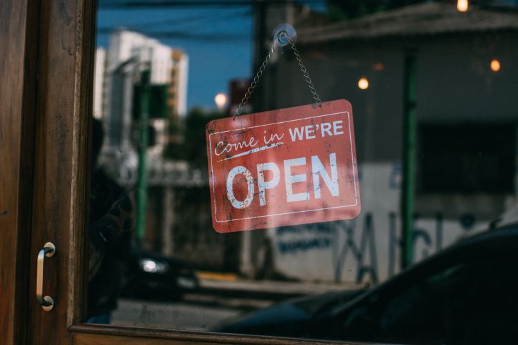 Red metal sign hanging in business window that reads 