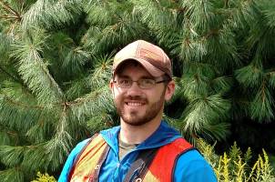 Jason Darling in the woods in orange vest and blue jacket