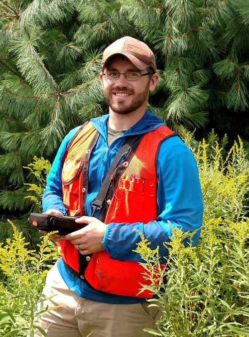 Jason Darling in the woods in orange vest and blue jacket