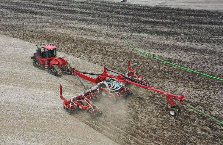 red tractor pulling equipment in an open farm field