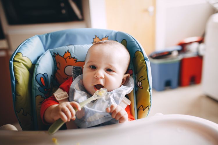 A baby eating in a highchair.