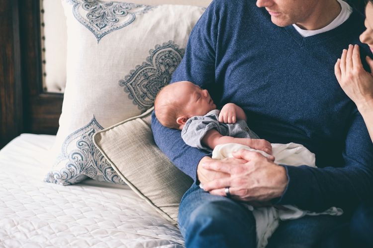 A man holding a tiny baby.