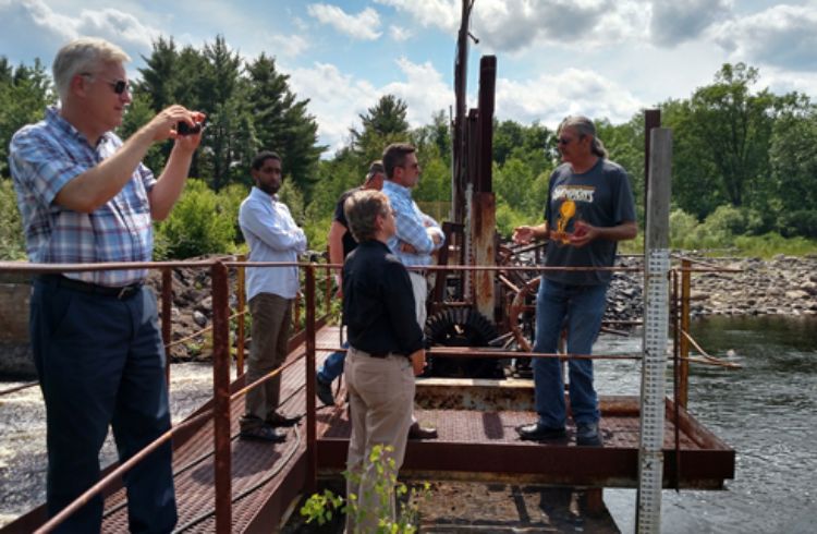 Photo of MSU and MDHHS standing on a dam in the Upper Peninsula, with officials from Marquette County discussing water fluctuation levels of the river.