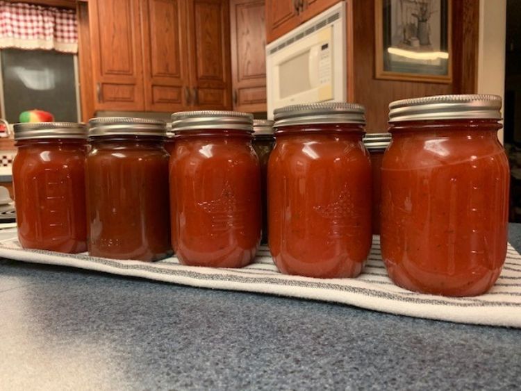 Jars of home-canned pasta sauce on a kitchen counter.
