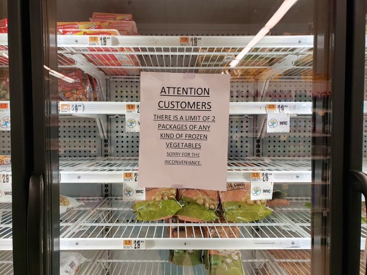 Sign showing frozen food vegetable package purchase limits in grocery store.
