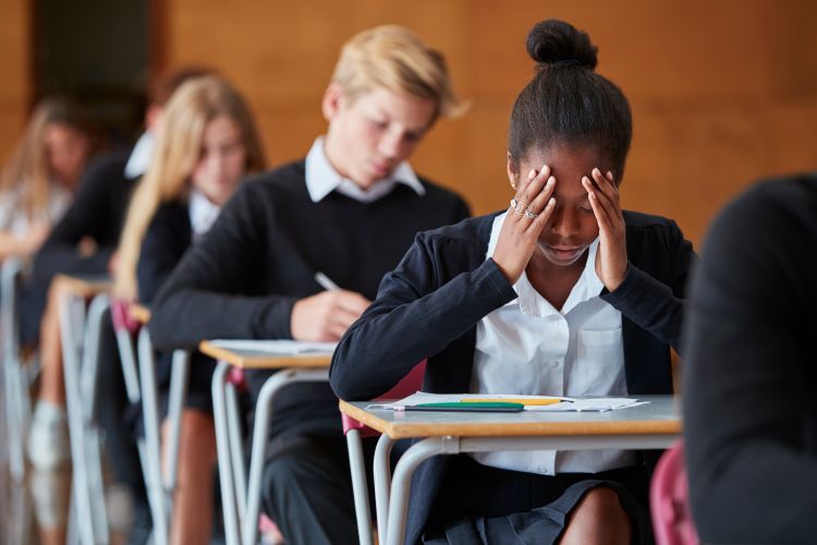 A girl in class with her hands on her face.