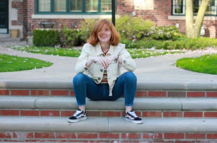 Lizzy Asker sitting on brick steps outside of a building.