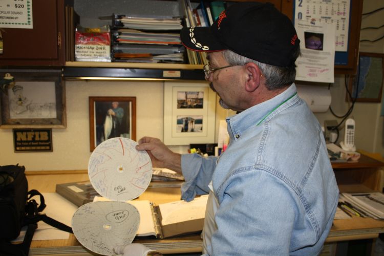 A fish processor checks smokehouse temperature recording charts. Photo: Ron Kinnunen | Michigan Sea Grant