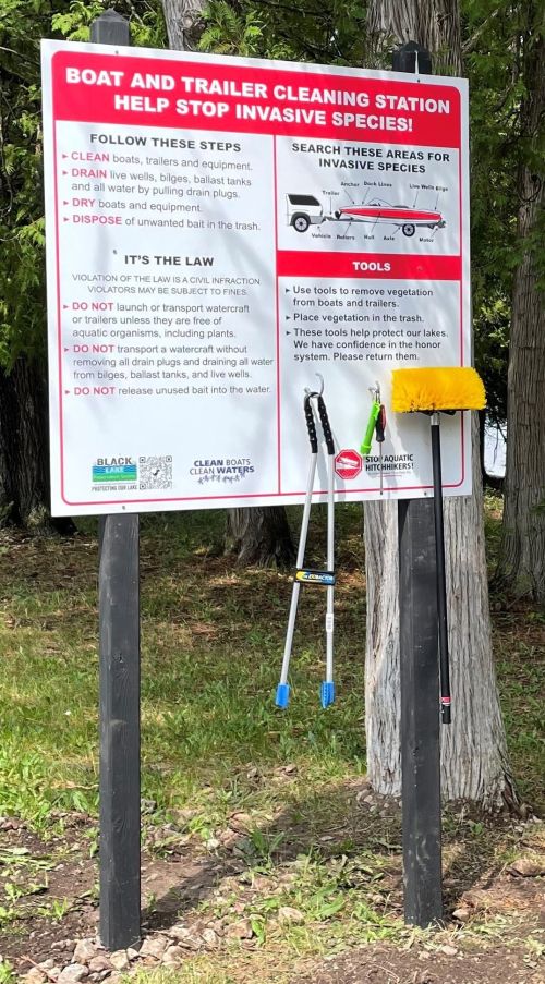 Boat and trailer cleaning station directional sign posted at Black Lake with tools.