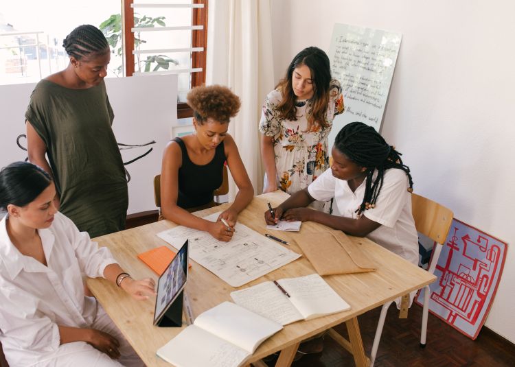 A diverse group of women working together on a plan.