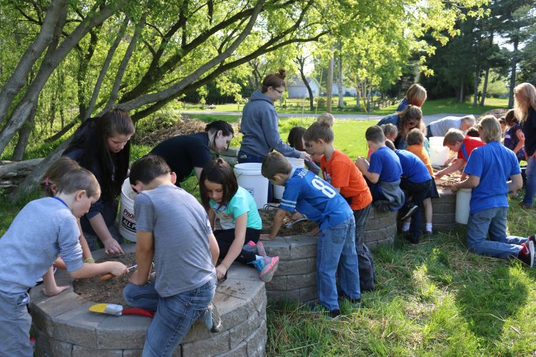 Youth pouring dirt in raised garden beds