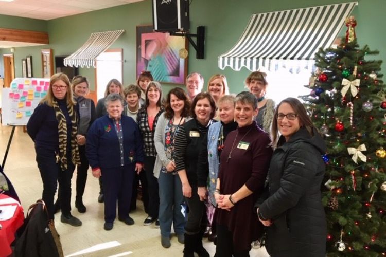 People standing by a decorated Christmas tree.