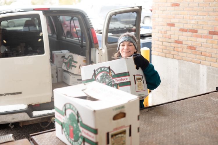 Person unloads boxes of produce from a van