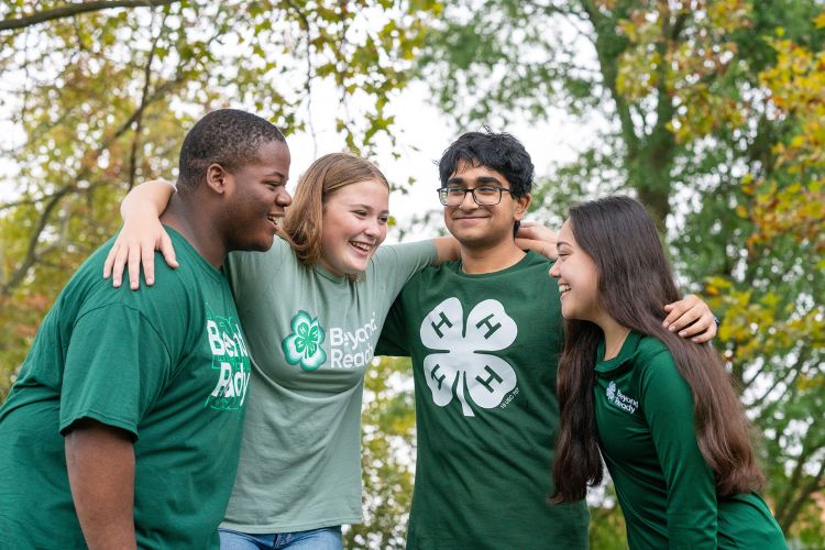 Four youth in 4-H gear with their arms around each other's shoulders.