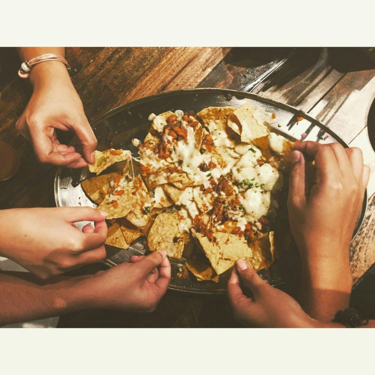 People dipping into a plate of nachos.