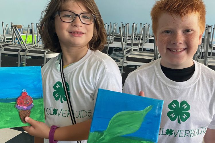 Two 4-H'ers holding up their art work they created at a 4-H event.