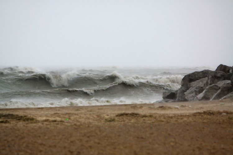 A view from a sandy beach on Lake Michigan looking out over the high waves and whitecaps during a storm.