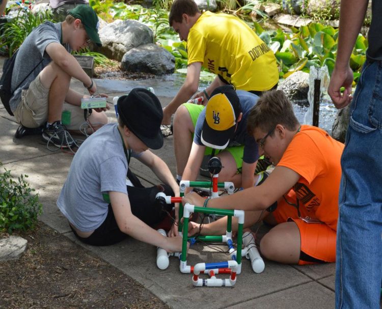 Youth work on building using pipes.