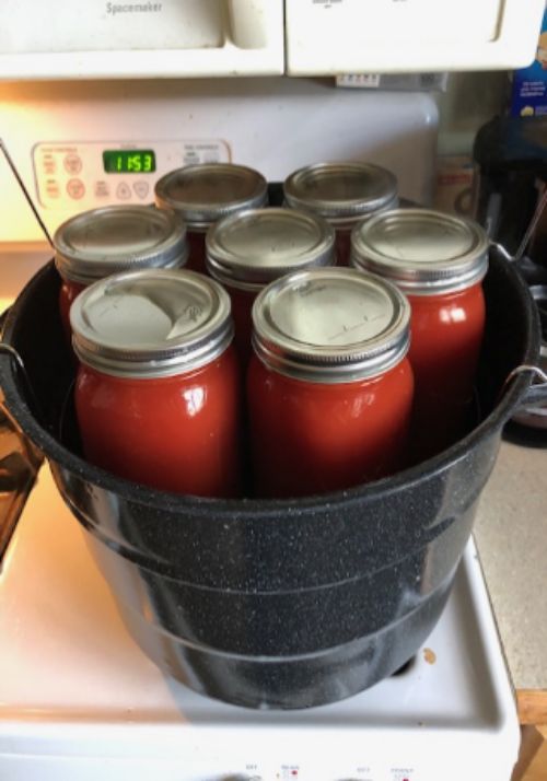 Multiple jars of canned tomatoes sitting on an oven.