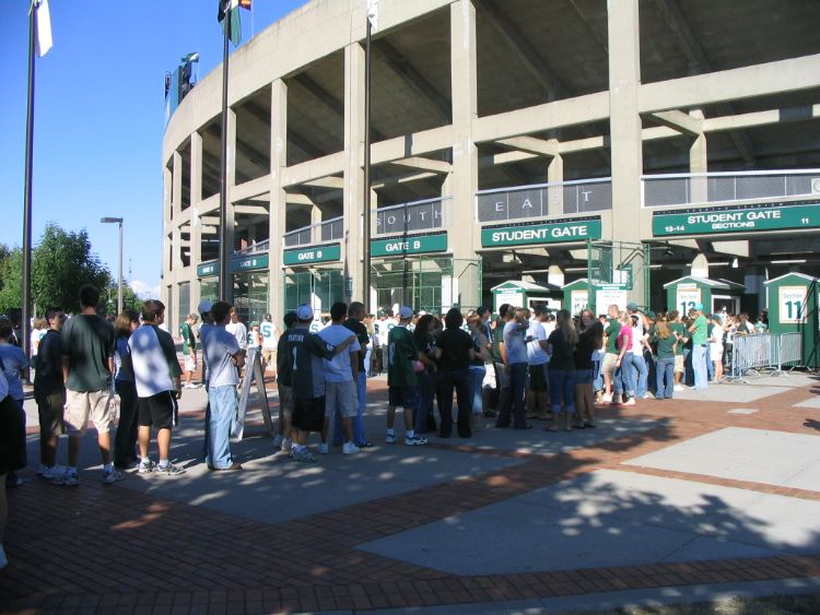 Fans stand in a line outside a stadium waiting to get in.