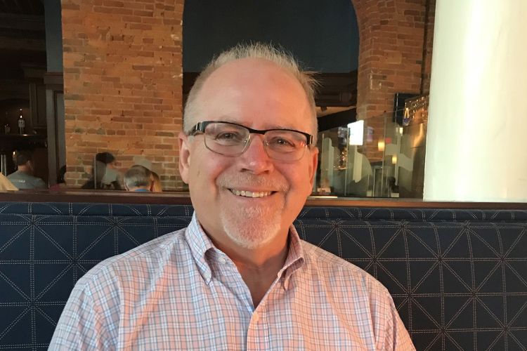 Tim Eder smiles while sitting in a booth at a restaurant.