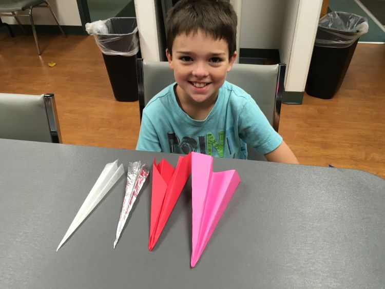 Alcona County 4-H club member with airplanes from four different types of paper.
